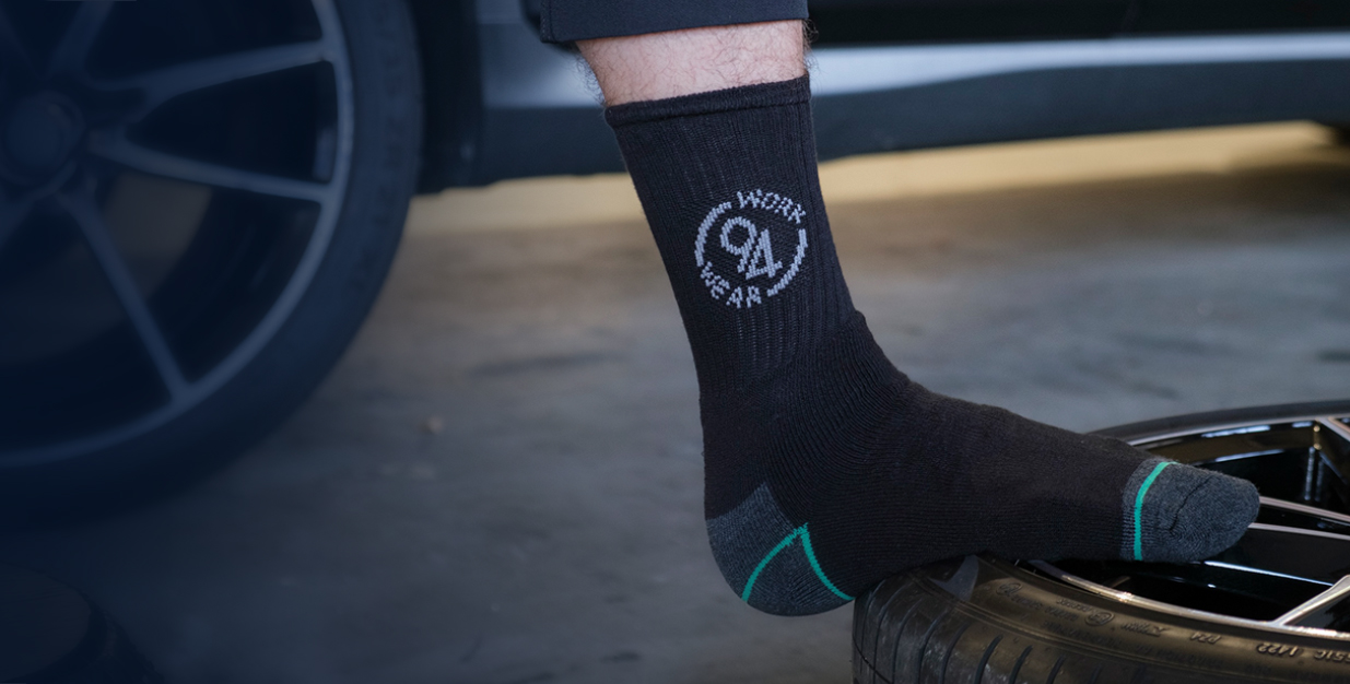 Zwarte 94Workwear sok gedragen naast een autowiel in de garage