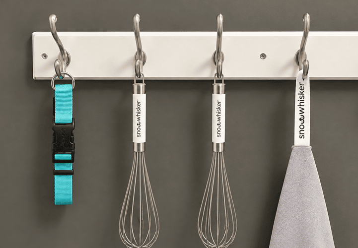 Whisks and a dog collar hanging from a wall rack