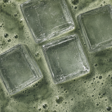 Close-up of ice cubes floating in a frothy green pea matcha drink
